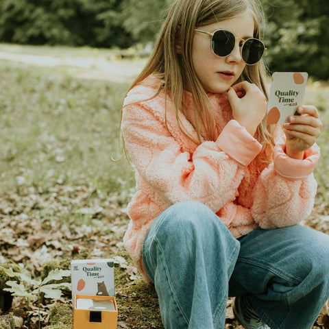Mädchen draußen mit einer Quality Time Kids-Karte